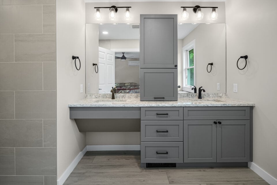 A remodeled bathroom finished with ash-colored cabinets and porcelain floors - bathroom remodeling