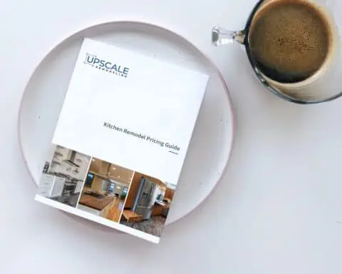 A Kitchen Remodel Pricing Guide by Upscale Remodeling in Ithaca NY sitting on a plate next to a cup of coffee