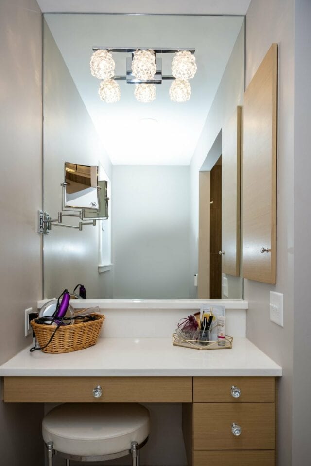 Remodeled vanity countertop area with light wood cabinets, swivel mirror and easy access to hair dryers and other accessories. Image: Upscale Remodeling.